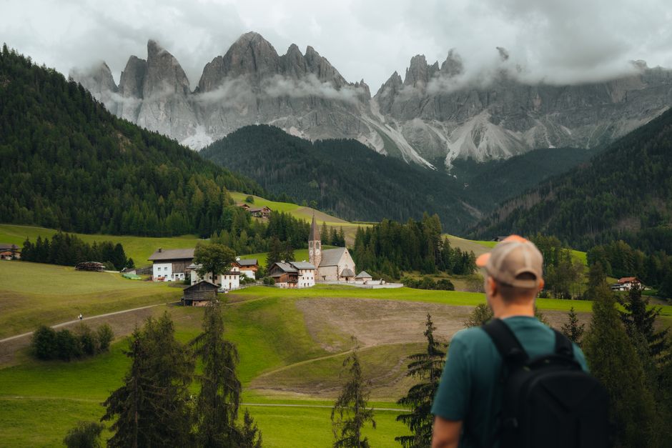 Traveler admiring a mountain village and scenic alpine views.