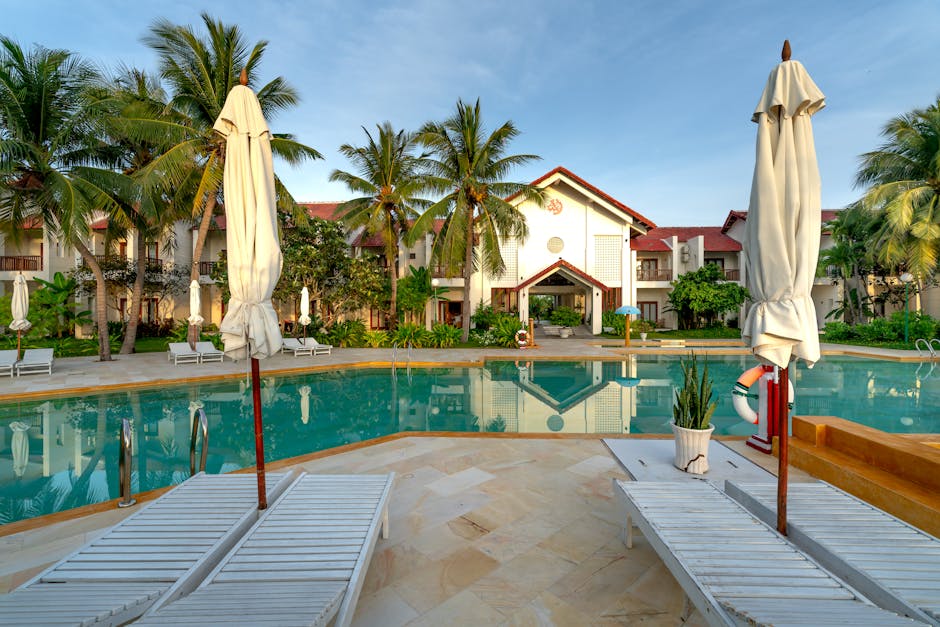 Tranquil luxury resort showcasing a serene pool, palm trees, and elegant architecture for a relaxing vacation.