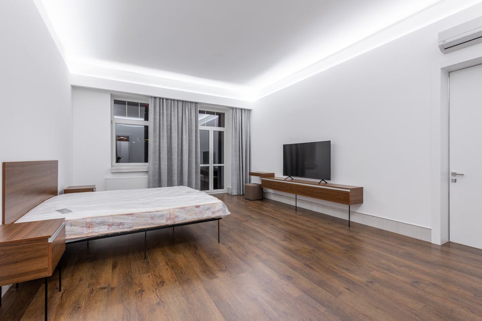 Spacious and stylish minimalist bedroom featuring sleek furniture, wooden flooring, and ambient lighting.