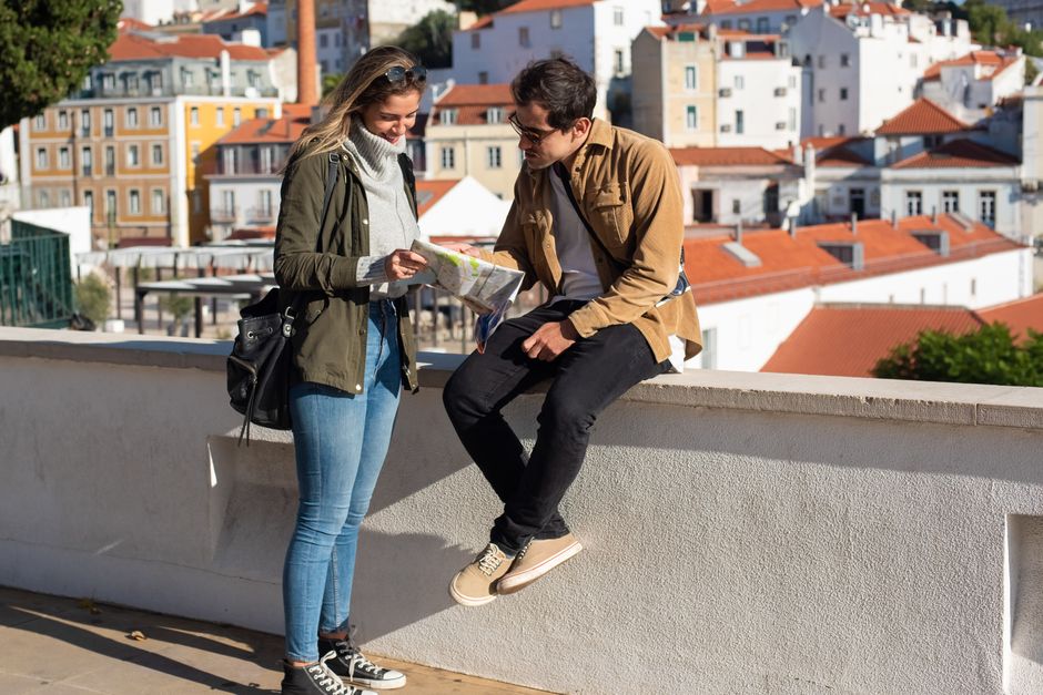 Two tourists using a map while sightseeing in a picturesque city with colorful buildings.