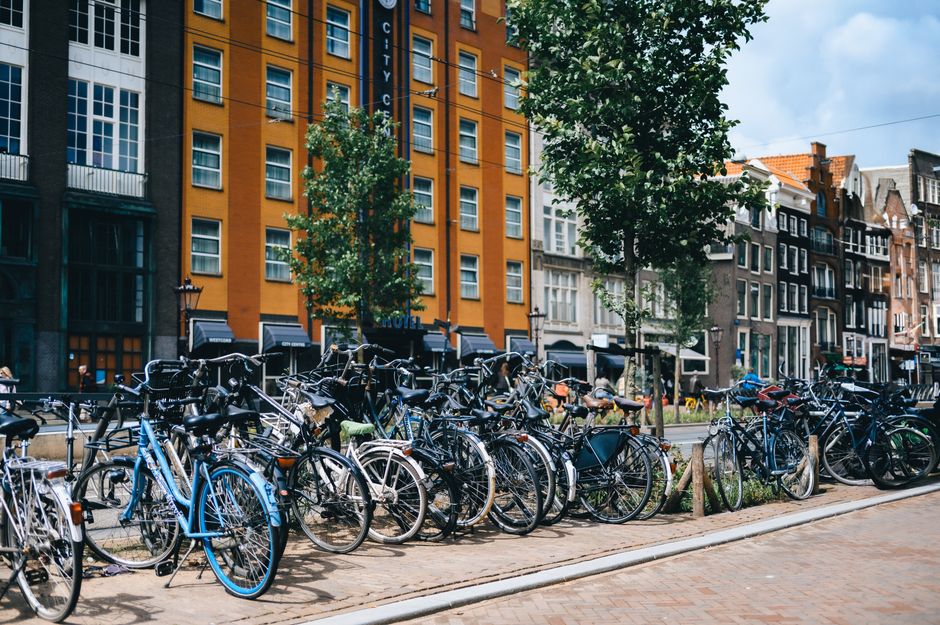 A vibrant city scene with many bicycles parked outside colorful buildings.