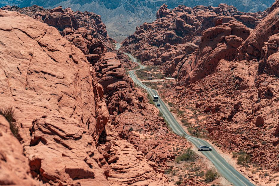A winding road cuts through the stunning red rock formations of a canyon, creating a breathtaking landscape view.