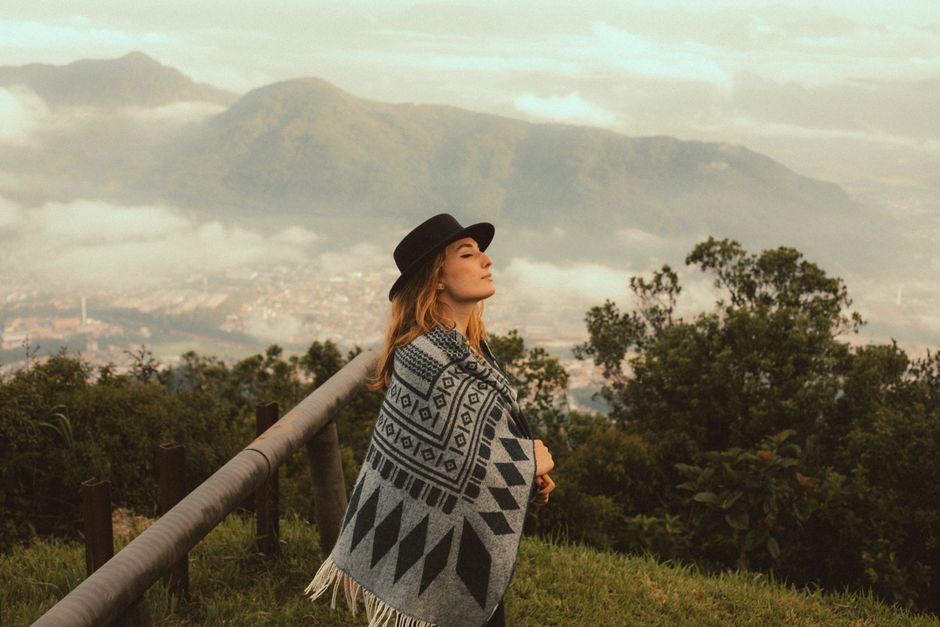 A young woman enjoys a tranquil moment in nature with a scenic mountain backdrop.