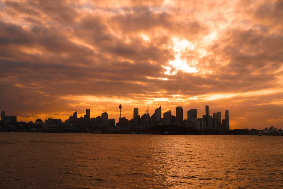 Stunning view of Sydney skyline silhouetted against a vibrant sunset with dramatic clouds.
