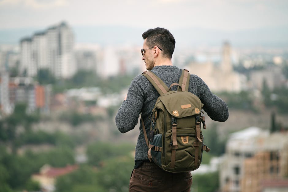 A male backpacker overlooks a cityscape, enjoying a travel adventure.