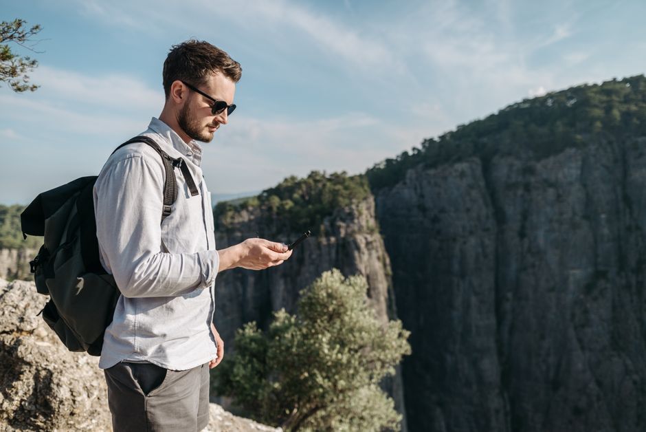 A young man with a backpack enjoys the rugged mountain scenery during a daytime hike.
