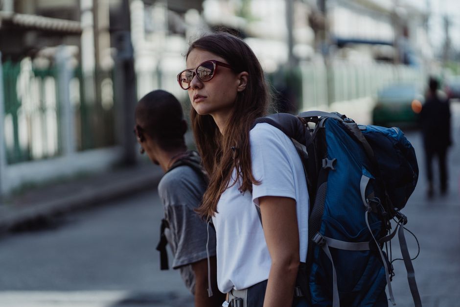 A young woman with a backpack explores the city, embracing urban travel and adventure.